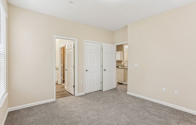 A room with white doors and carpeted floor.