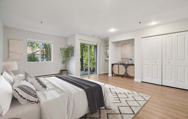 A bedroom with a large bed and a view of trees through the window.