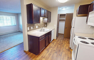 A kitchen with a white stove top oven and wooden floors.
