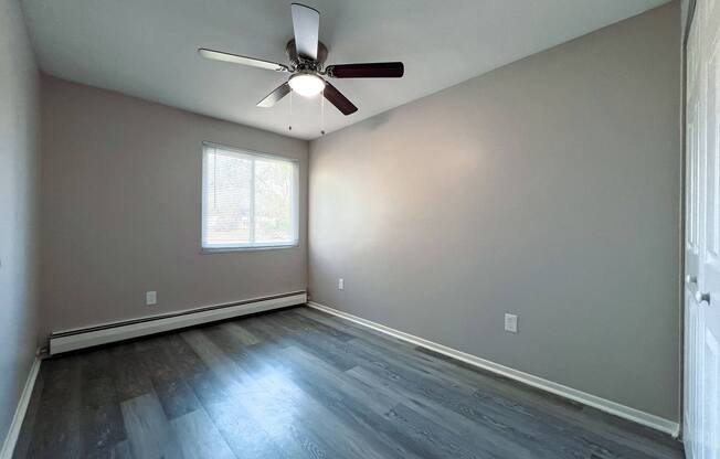 an empty living room with wood floors and a ceiling fan