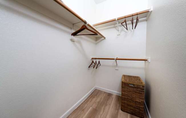 A white wall with a wooden hanger and a brown wicker basket.