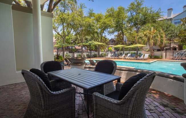 a patio with a table and chairs next to a swimming pool