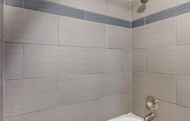 a white bath tub in a bathroom with tile walls at Troy Place Apartments - Troy, MI, Michigan