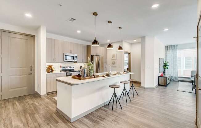 A modern kitchen with a white island and bar stools.
