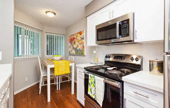 a kitchen with a stove and microwave and a table and chairs