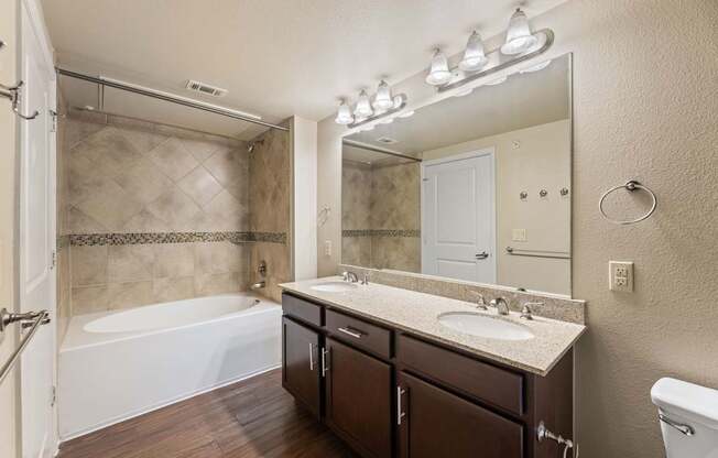 A bathroom with a tub, sink, and mirror.