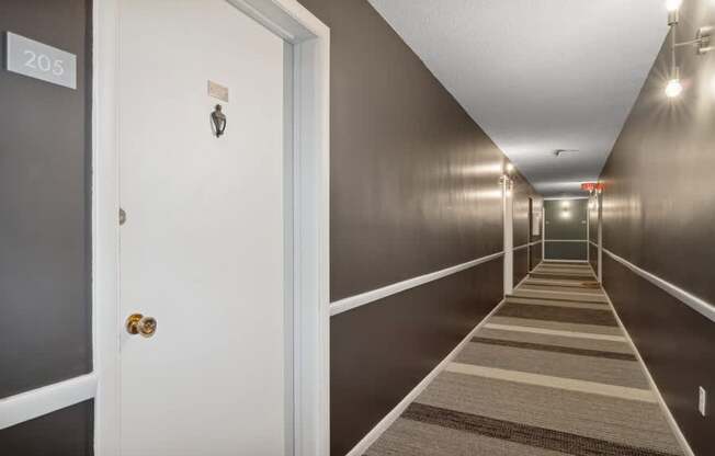 A hallway with a carpeted floor and doors on both sides.