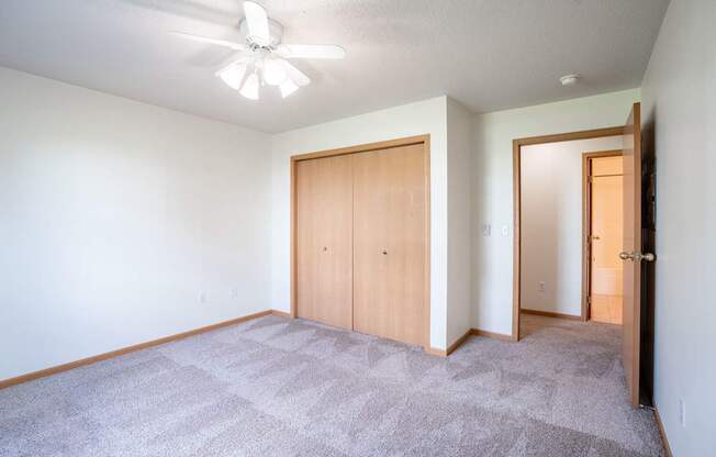 A room with a ceiling fan and carpeted floor. Fargo, ND Stonebridge Apartments