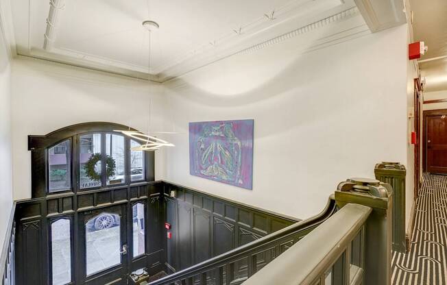 A staircase with a green railing and a purple painting on the wall.