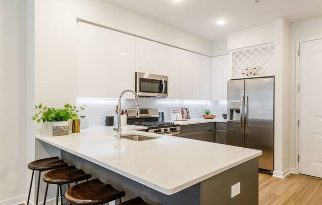 a kitchen with stainless steel appliances and an island with stools at One Ten Apartments, Jersey City , NJ, 07310