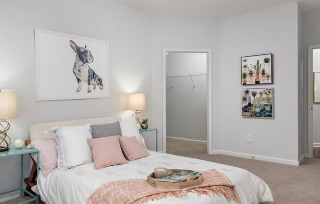 a bedroom with grey walls and a white bed with pink and grey pillows
