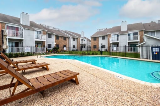 a swimming pool with two wooden benches next to an apartment building