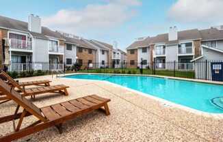 a swimming pool with two wooden benches next to an apartment building