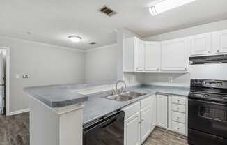 an empty kitchen with white cabinets and black appliances