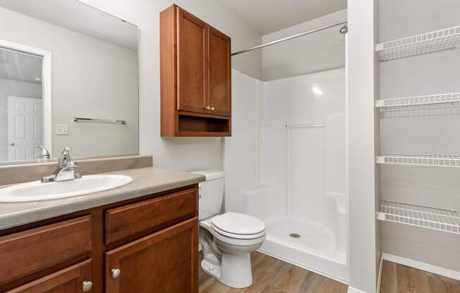 A white bathroom with a toilet, sink, and a walk-in shower.