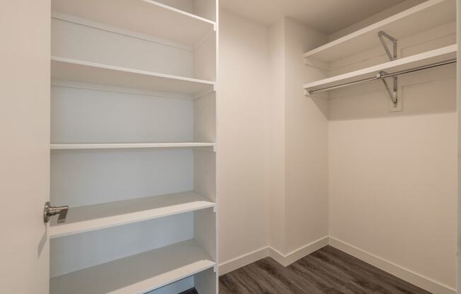 a walk in closet in a home with empty shelves