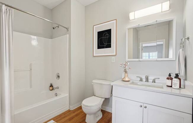 A white bathroom with a toilet, sink, and shower.