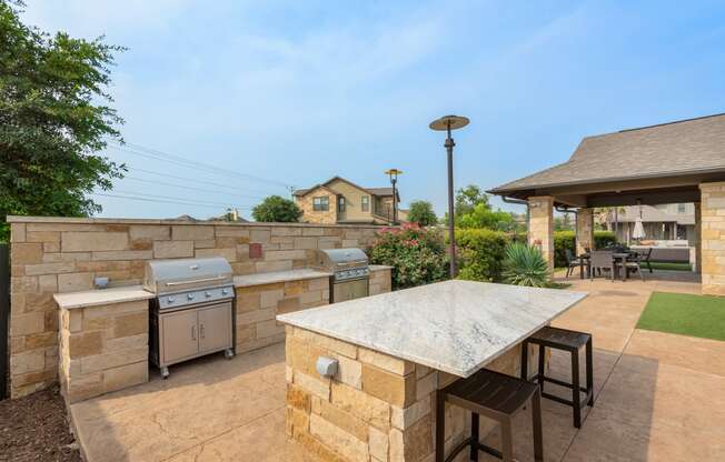 a patio with an outdoor kitchen and a stone wall
