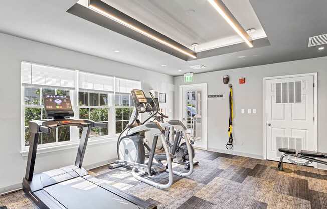 A gym with treadmills, exercise bikes, and a bench.