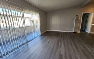 A room with wooden floors and a window with blinds.