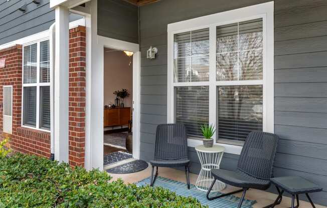 a front porch with two chairs and a small table