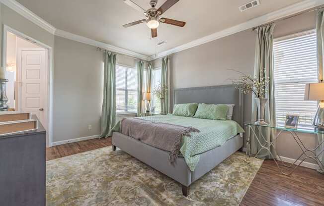 staged bedroom with hardwood-style flooring, windows, and ceiling fan