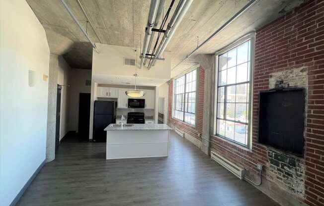 a large room with a kitchen and a brick wall