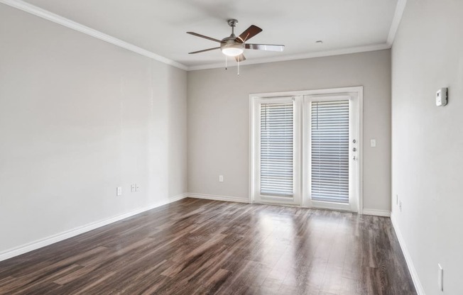 an empty living room with wood floors and a ceiling fan