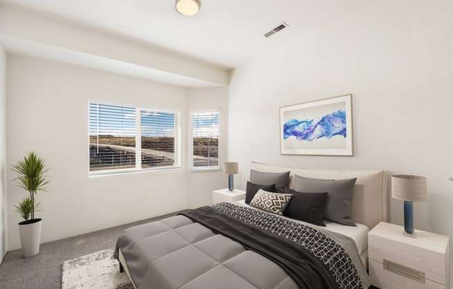 a bedroom with white walls and a large sunny window. Staged with a queen-size bed, side tables, and a plant. at Shoreline Village, Washington