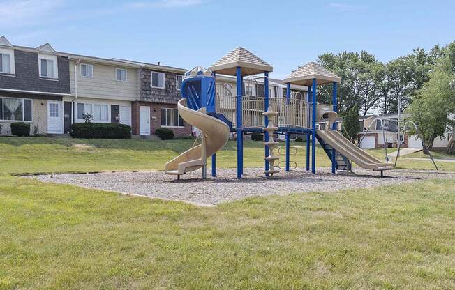 a playground with a slide and plently of grassy area to play around