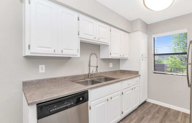 a kitchen with white cabinets and a stainless steel dishwasher