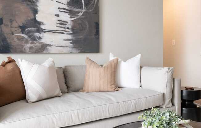 a living room with a gray couch and a black and white painting on the wall