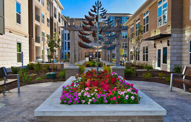 a planter with flowers and a metal tree in a courtyard