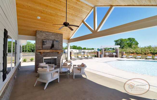 A poolside patio with covered seating area complete with fireplace and flat screen TV.