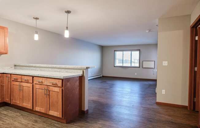 an empty living room and kitchen with wood floors and a counter top. Fargo, ND Urban Plains Apartments