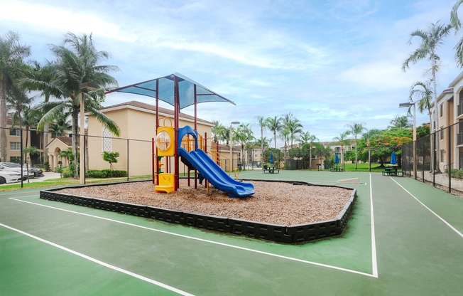 a playground with a blue and yellow swing set on a basketball court