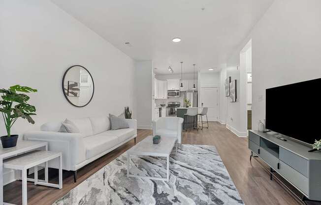 A modern living room with a white couch and a grey rug.