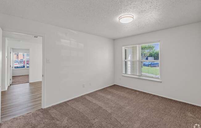 an empty living room with a large window and carpeting