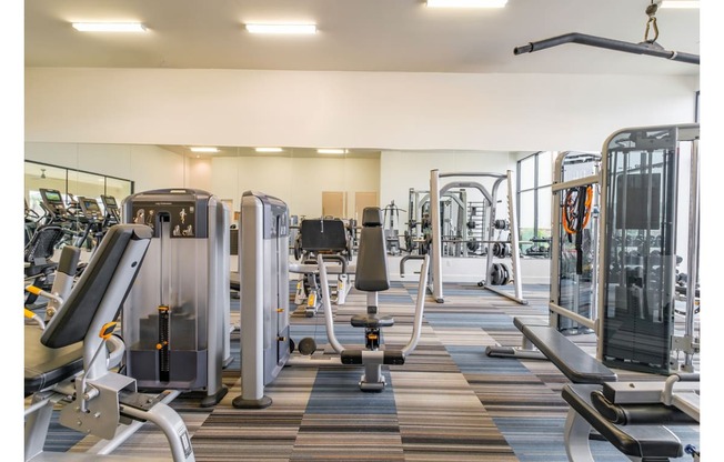 fitness center with cardio machines and weights at Reveal Skyline apartments