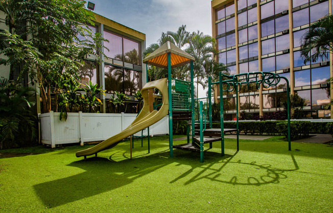 a playground with a slide next to a building at Palms of Kilani Apartments, Hawaii, 96786