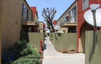 a sidewalk between two apartment buildings and a red fire hydrant