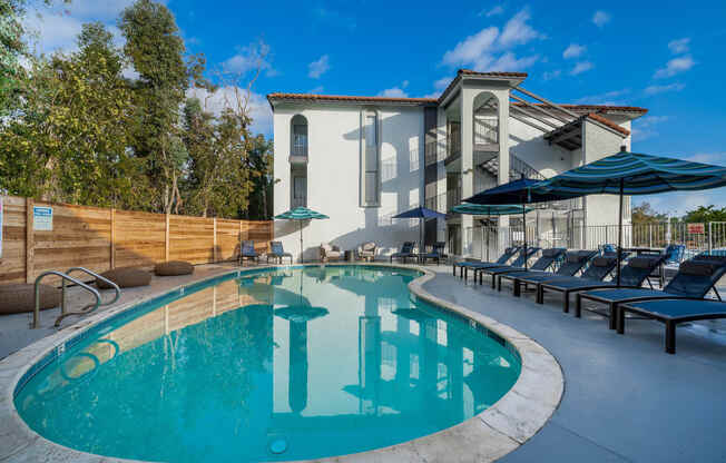 a swimming pool with lounge chairs and a building in the background