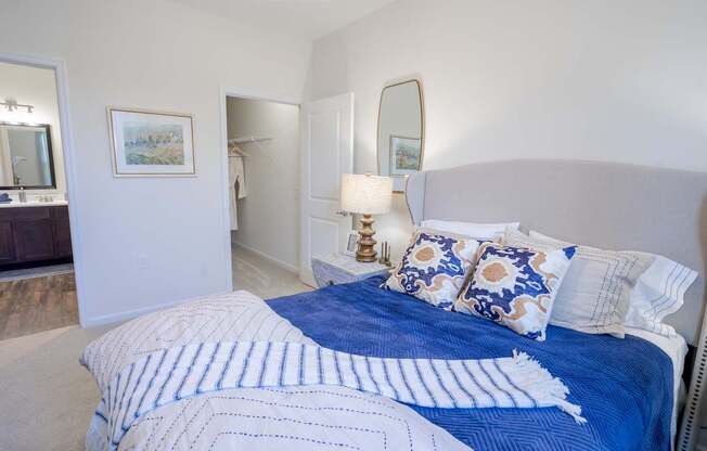 A bed with blue and white bedding and pillows in a bedroom.