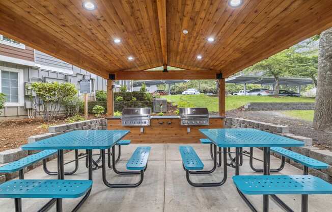 a covered patio with tables and chairs and a grill