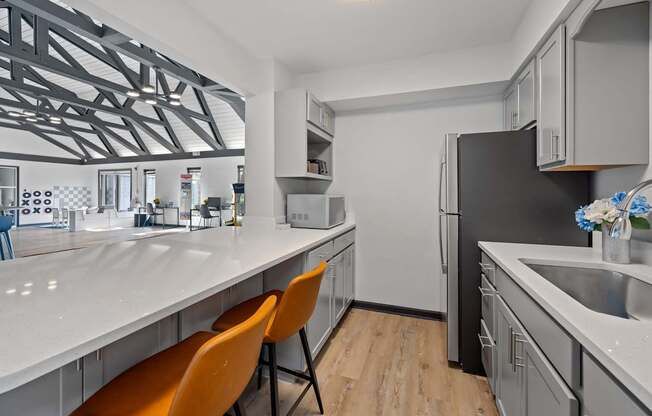 A modern kitchen with a white countertop and orange chairs.