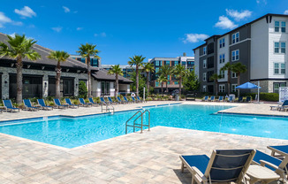 A swimming pool surrounded by lounge chairs and palm trees.