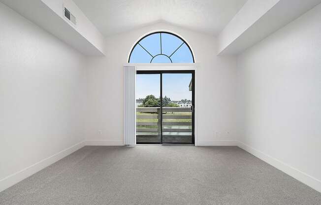 A living room with a cathedral ceiling and large arched window and a view at The Crossings Apartments, Grand Rapids, MI, 49508