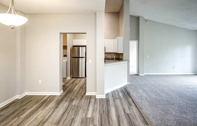 an empty living room and kitchen with wood flooring