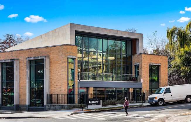 a building with large glass windows and a woman crossing the street