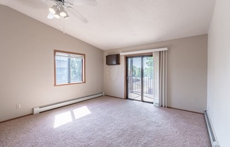 an empty living room with a sliding glass door to a balcony. Fargo, ND Rosegate Apartments